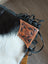 Tan leather hand tooled patch with floral design attached to black smoky charcoal fringed strap on tumbleweed #4 tassel purse