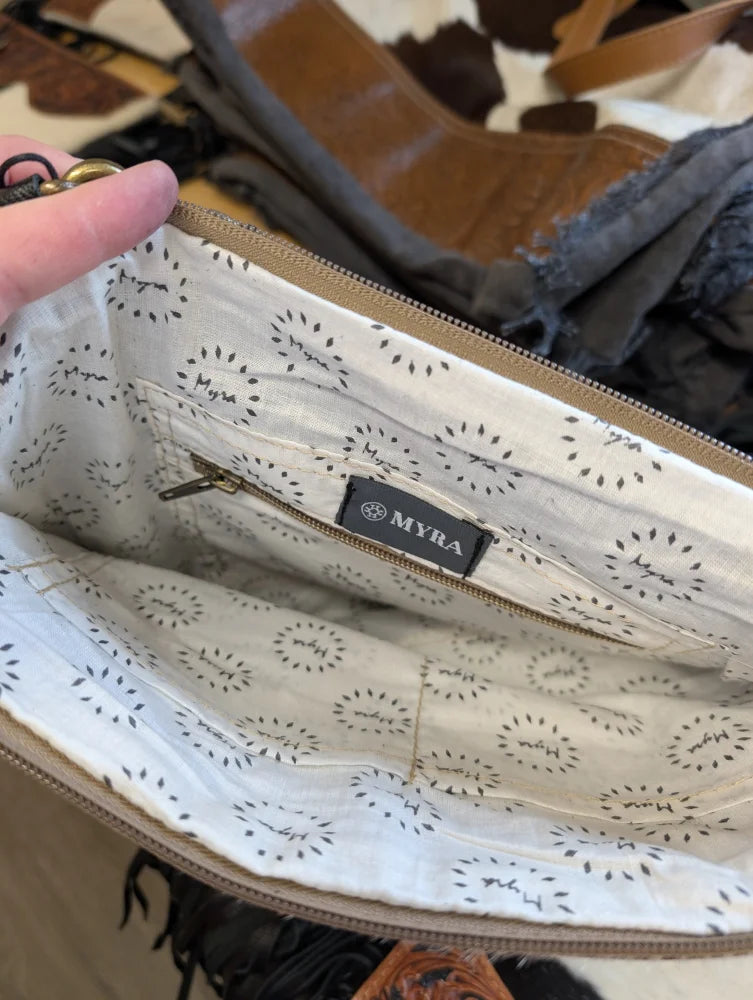Cream-colored lining with black dandelion pattern inside tumbleweed 4 purse featuring myra label and gold zipper pocket
