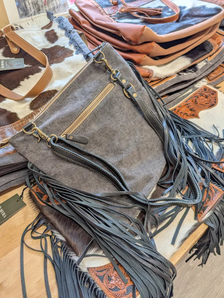 Gray denim crossbody tumbleweed 5 purse with smoky charcoal hand tooled leather fringe and zippered pocket brass hardware