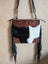 Tumbleweed 5 black and white cowhide crossbody bag with hand tooled brown floral embroidery and smoky charcoal fringes with zippered pocket