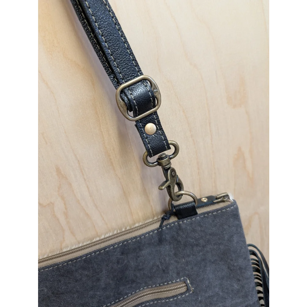 Dark blue denim tumbleweed 5 crossbody bag with hand tooled smoky charcoal leather strap and zippered pocket