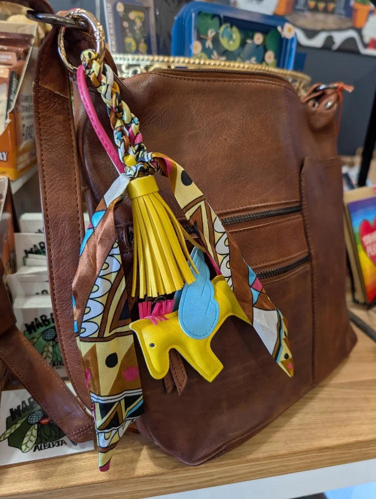 Brown leather crossbody bag with colorful patterned scarf and yellow tassel charm part of bag charms deal