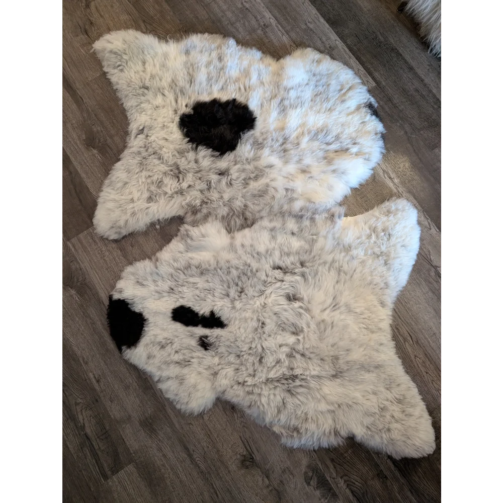 Two icelandic spotted sheepskins in white and black resembling a bear shape with soft short wool texture