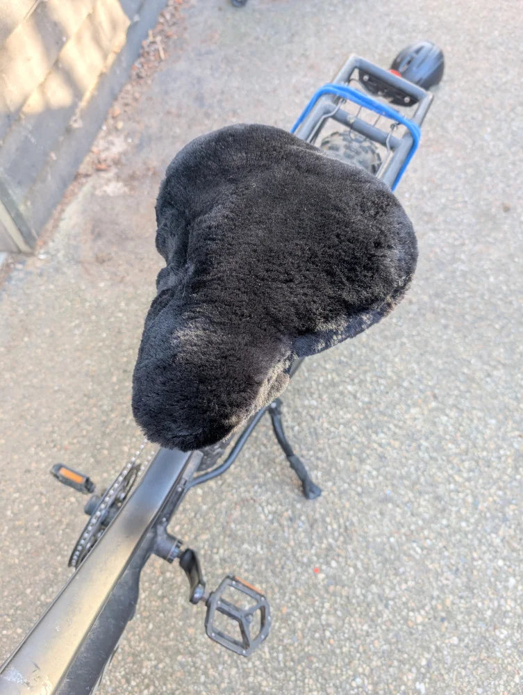 Black fuzzy merino sheepskin bicycle seat with blue accents and silver pedals