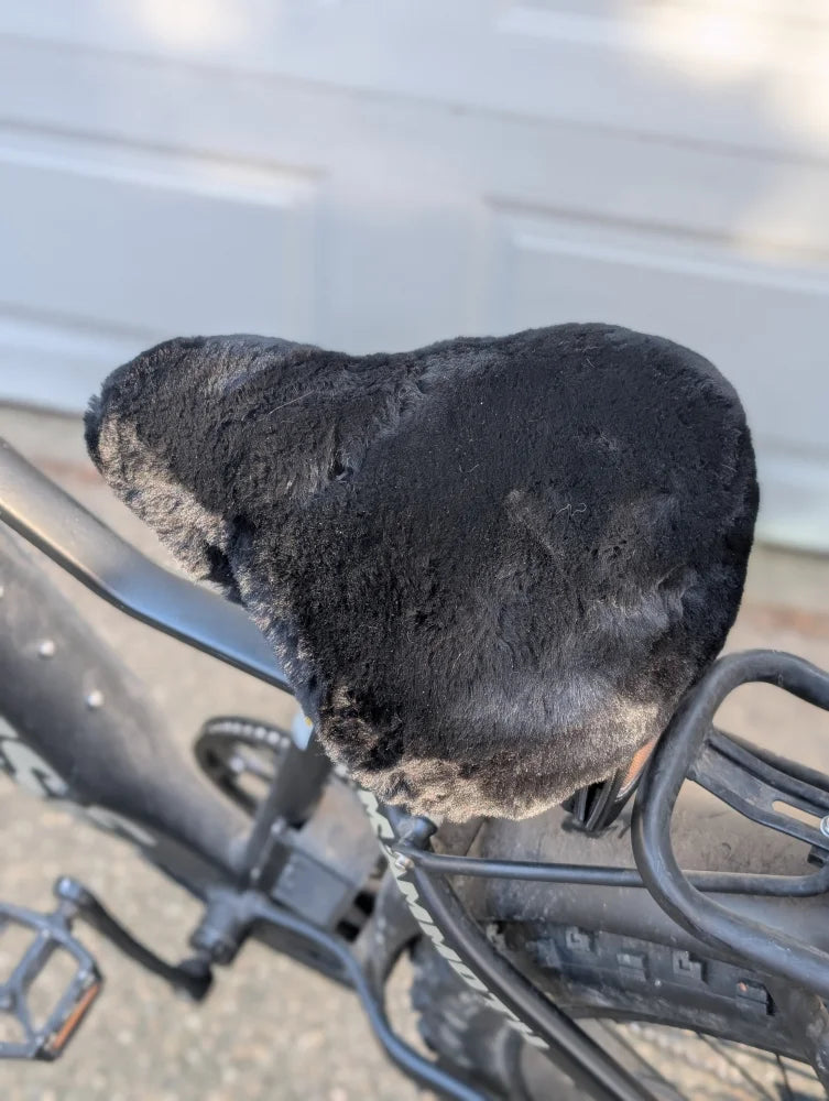 Worn black leather bike saddle with merino sheepskin cover