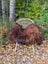 A cozy massive natural dark rusty icelandic sheepskin wool throw draped over a light wicker chair with metal legs