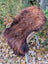 Thick fluffy wool icelandic sheepskin rug in natural dark rusty color draped over wicker chair for cozy decor