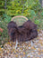 A cozy dark rusty icelandic sheepskin throw draped over a woven rattan chair with white metal legs