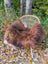 Cozy fluffy brown and white wool icelandic sheepskin throw draped over woven wicker chair with metal legs