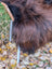 A plush long-haired highland cow with curved horn on a massive natural dark rusty wool icelandic sheepskin rug