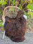 A dark rusty icelandic sheepskin rug with soft wool texture on a wicker chair seat perfect for cozy use