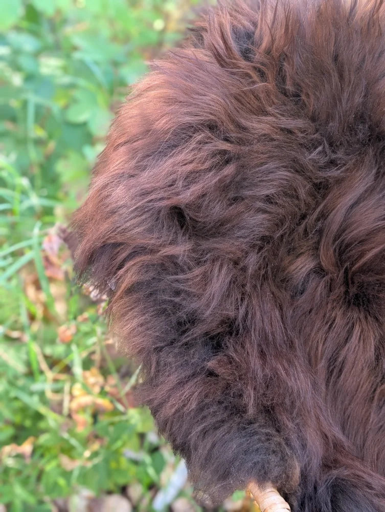 A thick shaggy brown wool icelandic sheepskin coat with soft textured natural dark rusty fur for warmth