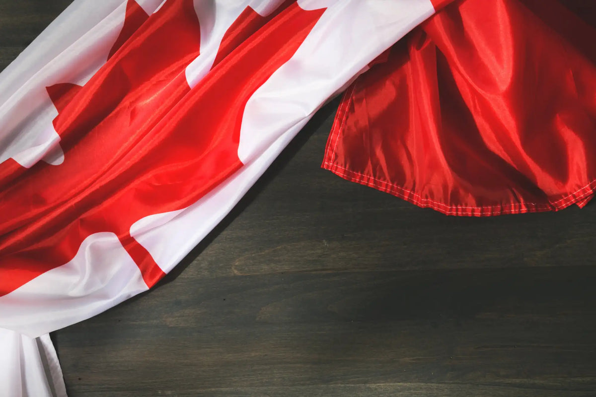 A vibrant red and white canadian flag, made of glossy satin fabric with a prominent maple leaf design.