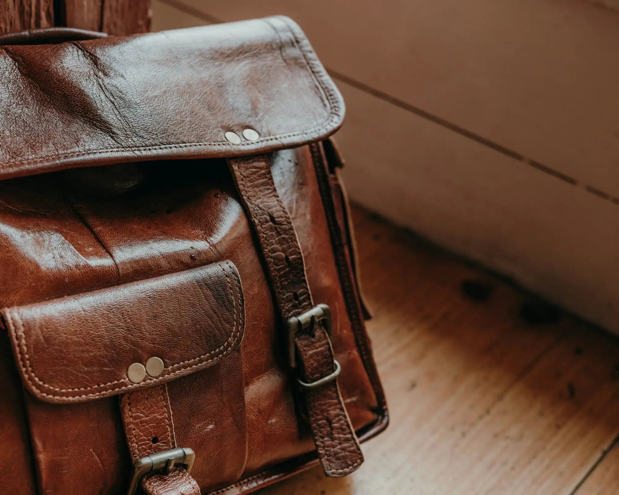 A well-worn brown leather satchel with brass hardware and a flap closure.