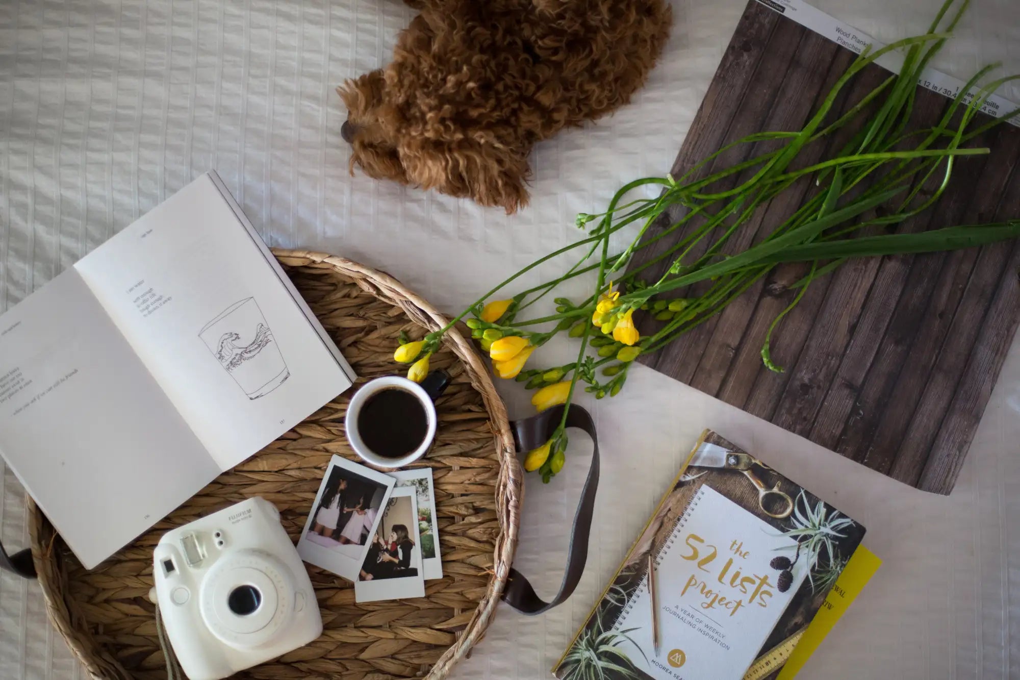 White instant camera with a circular lens and rounded edges, resting on a woven tray.