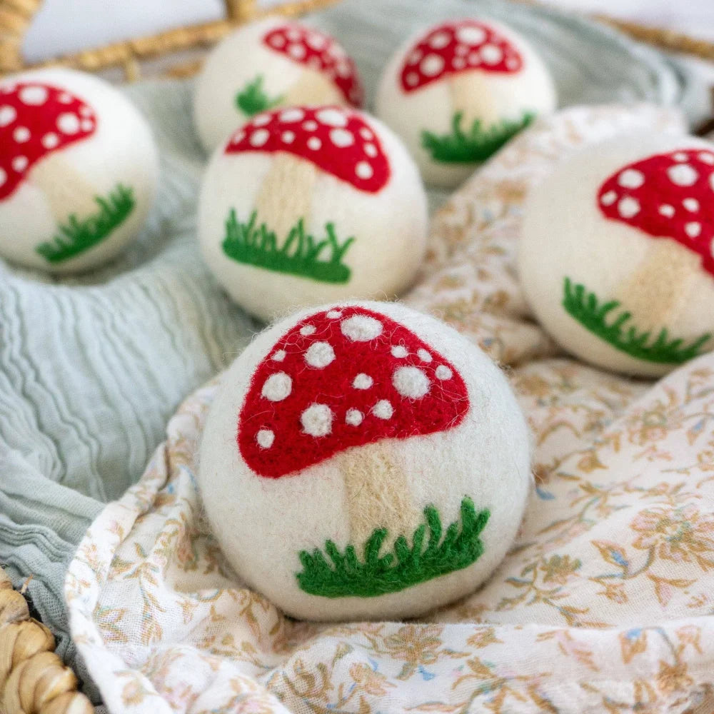 White felted wool dryer balls hand-painted with red mushroom and green grass by angus oliver for dryer sheets use