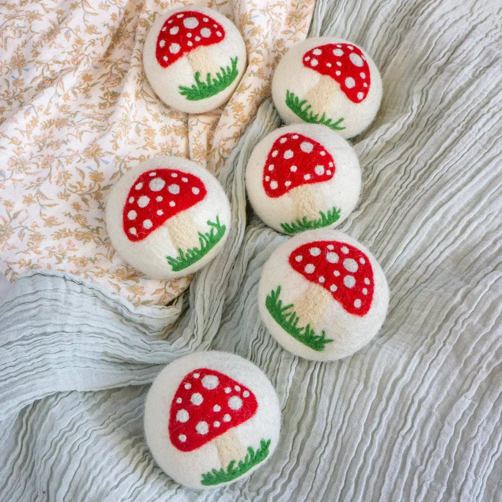 White mushroom trio dryer balls with felted red caps dotted in white and green grassy bases by angus oliver