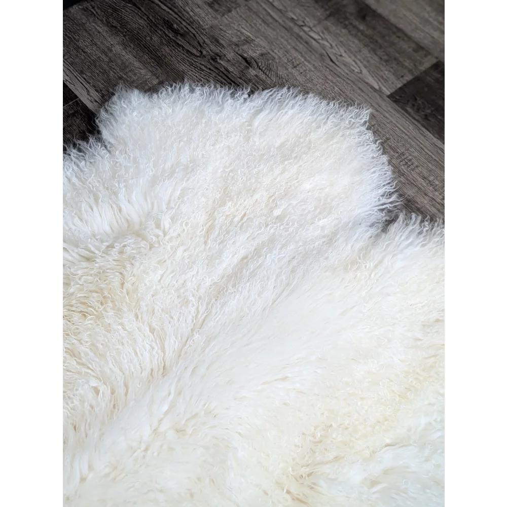 Gorgeous natural white Mongolian sheepskin rug on dark wood floor