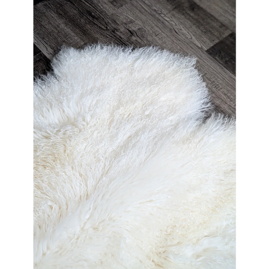 Gorgeous natural white Mongolian sheepskin rug on dark wood floor