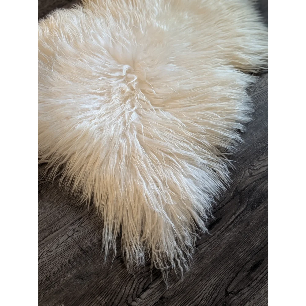 Cream-colored soft icelandic sheepskin rug with long fibers on dark wood floor rug 53x34 inches grade a quality