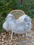 A cozy fluffy gray icelandic sheepskin long wool throw draped over a woven rattan chair with white metal legs