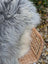 A long wool icelandic sheepskin rug in natural grey draped over a woven wicker chair for cozy decor