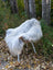 A fluffy white faux fur chair with woven wicker seat and metal legs outdoors featuring a massive icelandic sheepskin