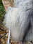 A plush long wool icelandic sheepskin throw in natural grey draped over a wicker chair backrest
