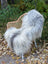 A plush gray and white long wool icelandic sheepskin throw draped over a woven wicker chair for cozy decor