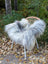 A fluffy long wool icelandic sheepskin throw in natural grey draped over a wicker chair for cozy decor