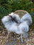 Fluffy natural grey icelandic sheepskin rug with long wool draped over a woven rattan chair