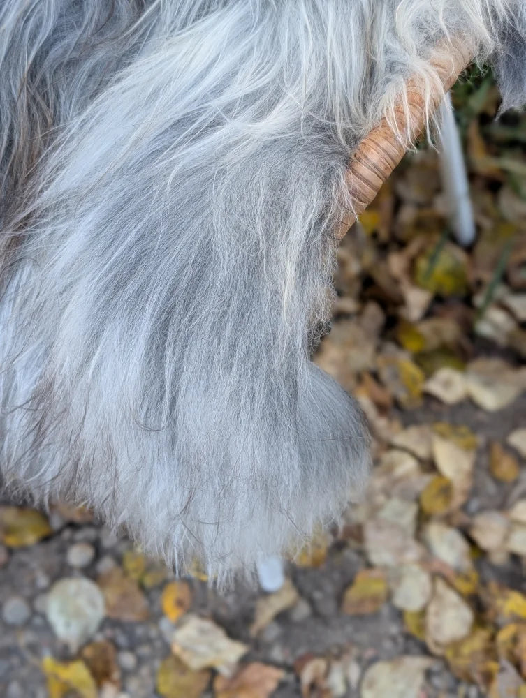 A fluffy long wool icelandic sheepskin in natural grey with silvery fur and a woven handle for easy carrying