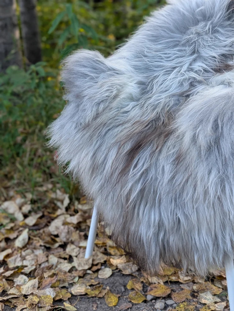 A plush light gray icelandic sheepskin throw with long wool icelandic texture draped over a white chair leg