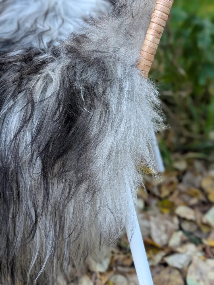 A plush long wool icelandic sheepskin in natural grey attached to a woven bamboo handle accessory