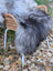 A massive icelandic sheepskin rug in natural grey draped over a wicker chair with white metal legs