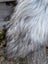 A thick shaggy gray and white massive icelandic sheepskin draped over a wooden post showcasing natural wool icelandic sheepskins