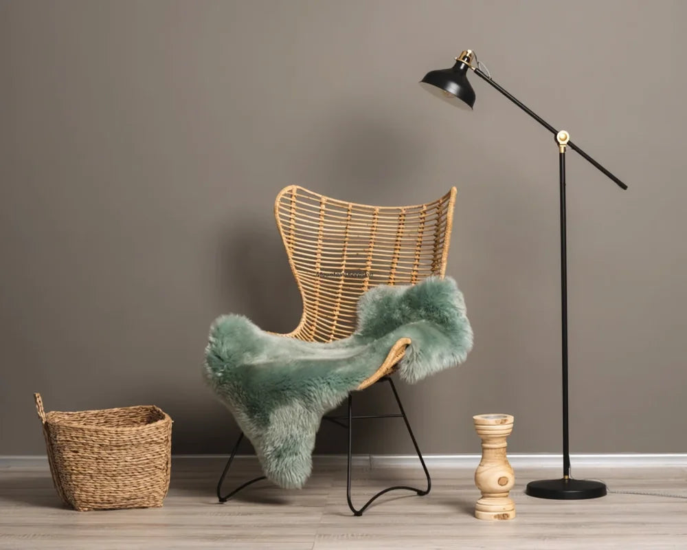 Wicker butterfly chair with black metal legs draped in teal dyed merino sheepskin throw meeting european standards