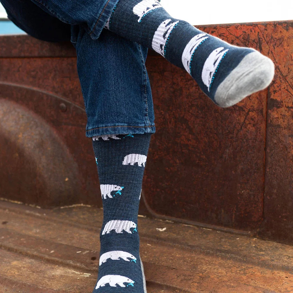 Women’s dark blue merino wool socks with white polar bear designs and teal accents worn with rolled-up denim jeans