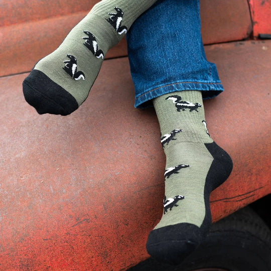 Olive green merino wool socks with black and white skunk patterns and reinforced black toe caps for women