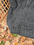 A cozy dark gray calgary cardigan in zealand wool with cable knit texture and ribbed cuffs, no attached hood visible