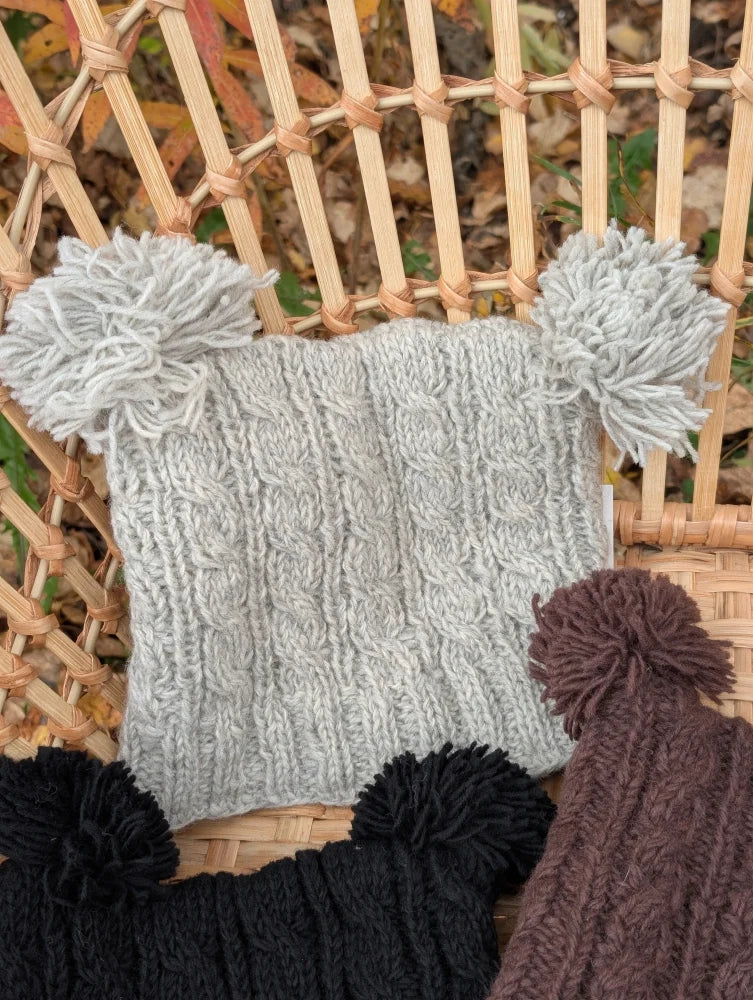 Gray woolen heelah double pompom hat with cable knit texture and fluffy double pom poms on each end