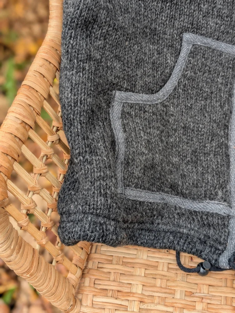 A dark gray knitted drawstring bag with lighter gray stitched pocket outline and black closure perfect for jasper vest use
