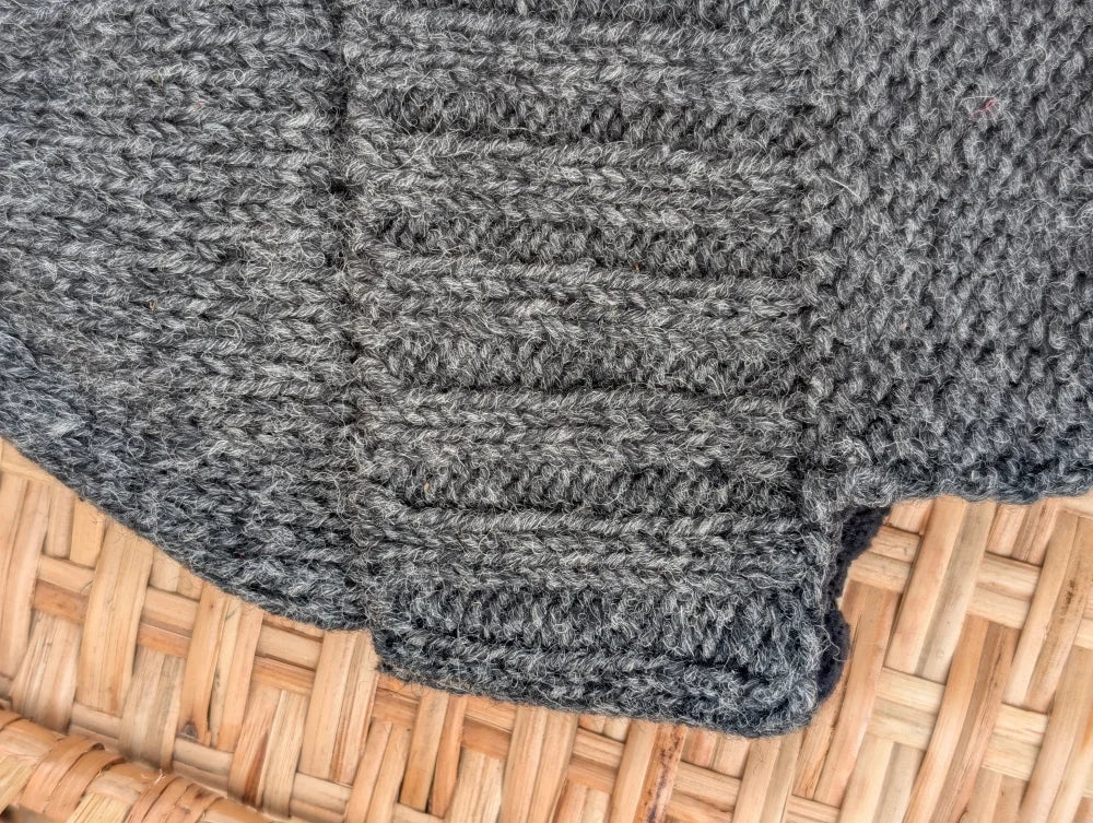 A chunky heather gray woolen solo ear flap hat with ribbed texture and visible stitch pattern