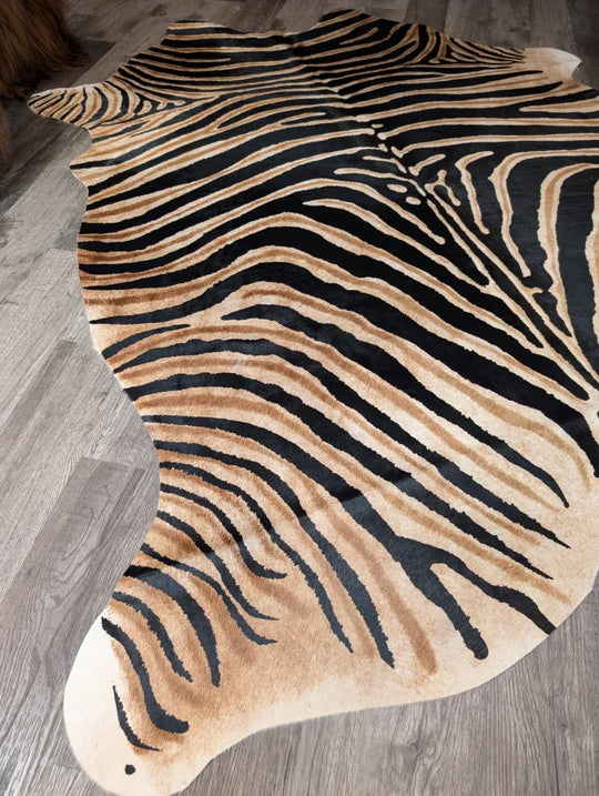 A gorgeous zebra printed large cowhide rug by angus oliver featuring plush faux fur with unique black and tan stripes