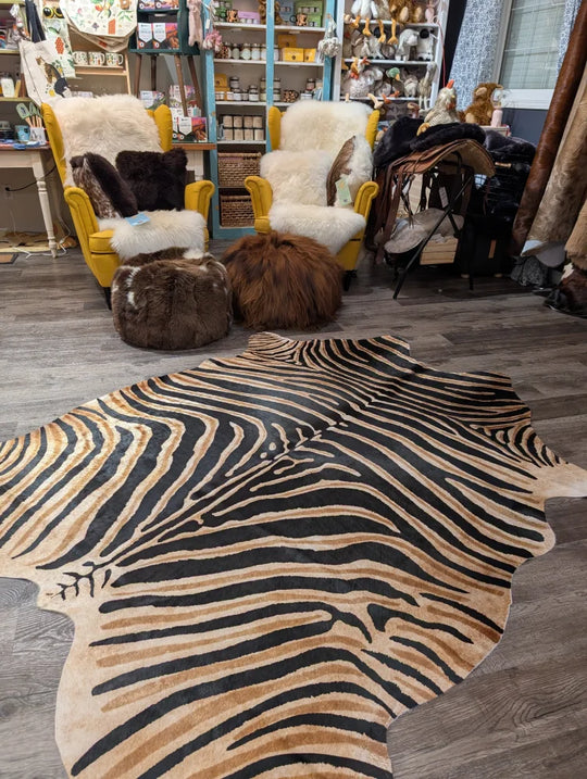 Gorgeous zebra printed large cowhide rug by angus oliver with bold black and tan stripes and unique characteristics on wood floor
