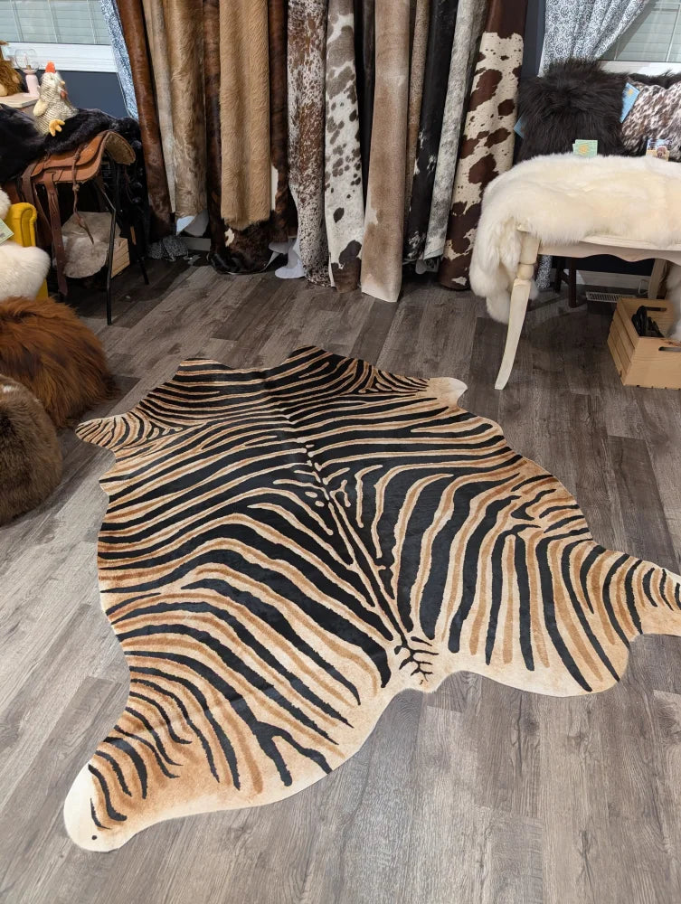 Gorgeous zebra printed cowhide rug by angus oliver with bold black and tan stripes and unique characteristics on wooden floor