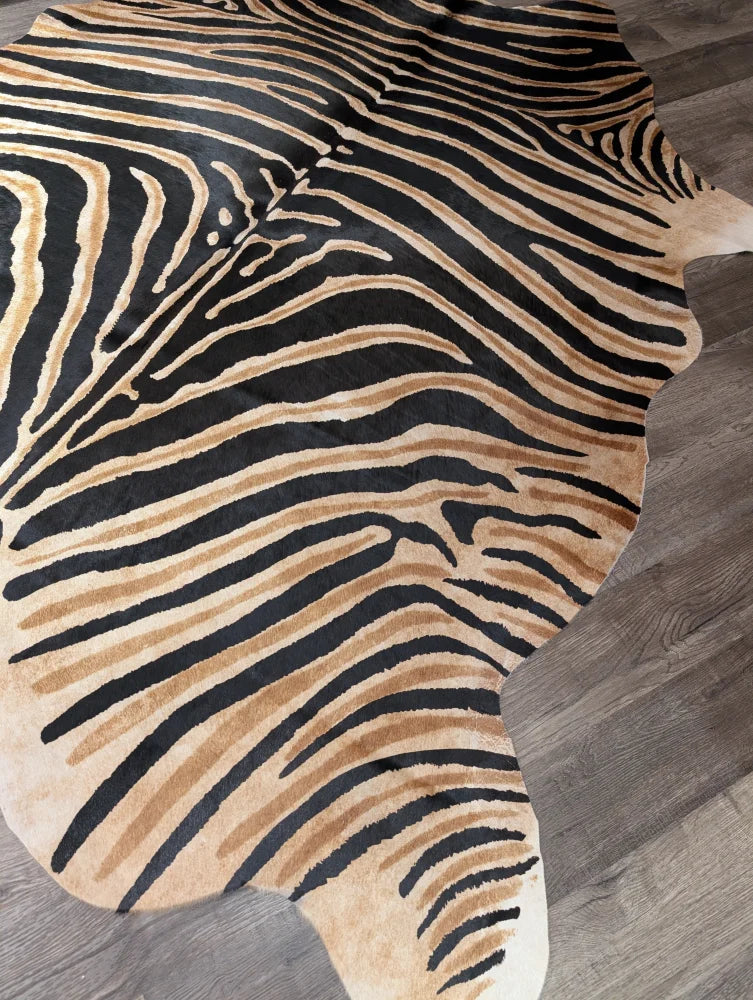 Gorgeous zebra printed cowhide rug by angus oliver with bold black and tan stripes on gray wood floor featuring unique characteristics