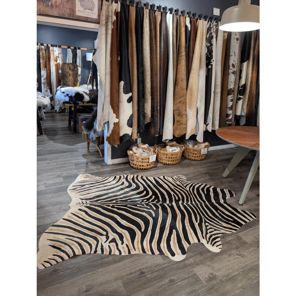Large cowhide zebra print rug with bold black and beige stripes on wooden floor by angus oliver