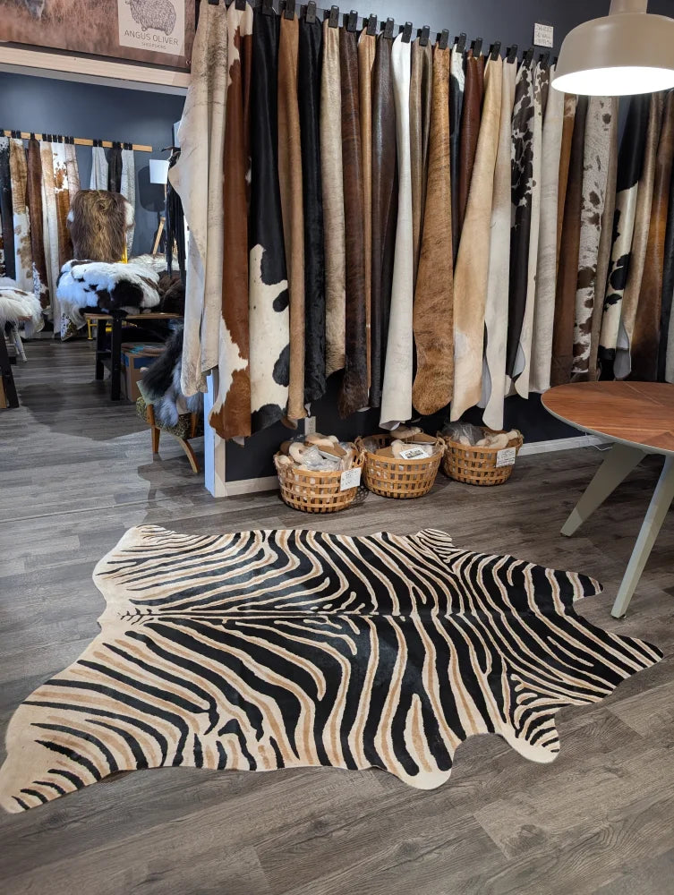 Large cowhide zebra print rug with bold black and beige stripes on wooden floor by angus oliver