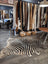 Large cowhide zebra print rug with bold black and beige stripes on wooden floor by angus oliver